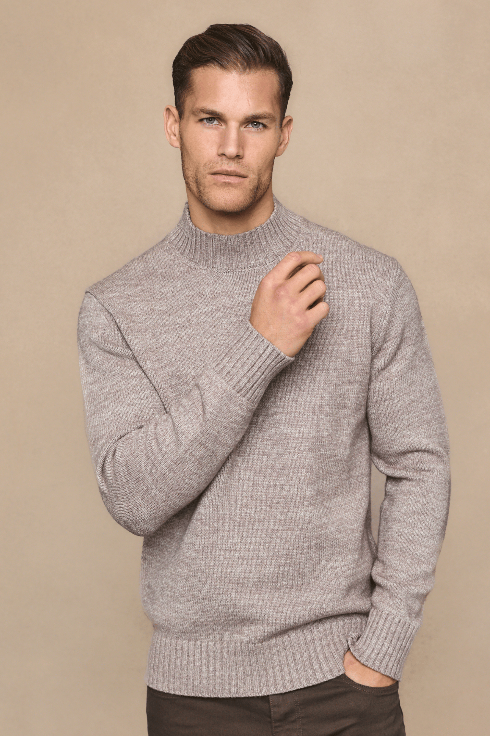 Man wearing a light brown sweater against a beige background